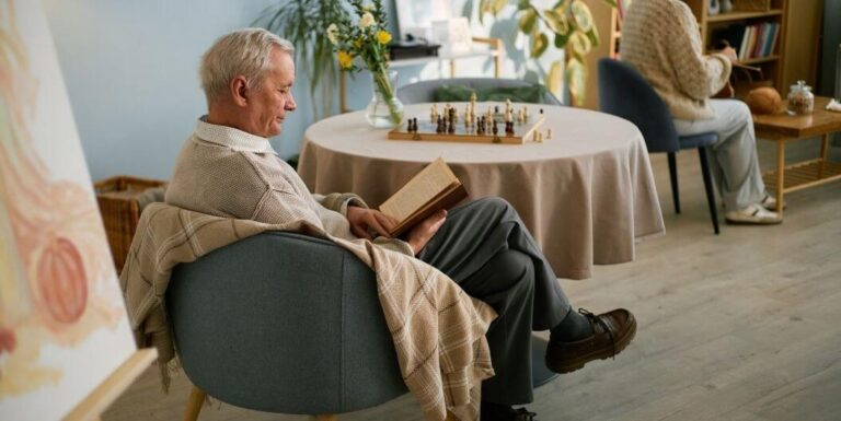 Elderly Man Reading Book in Cozy Room at Senior Living Facility